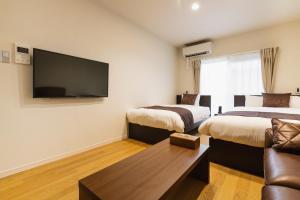 Habitación de hotel con 2 camas y TV de pantalla plana. en Cocolie BEPPU, en Beppu