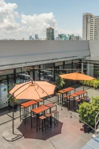 a group of tables with orange umbrellas on a roof at Amelie Hotel Manila in Manila