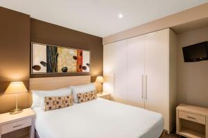 a hotel room with a white bed and white walls at Apartments @ 16 Holdfast in Glenelg