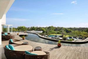 a resort with a pool and tables and chairs at Swiss-Belresort Pecatu in Uluwatu