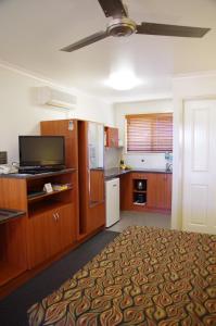 a large kitchen with wooden cabinets and a television at Stannum Lodge Motor Inn in Stanthorpe