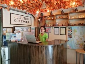 a man sitting at a counter with a laptop at Cliffside Cottages in El Nido