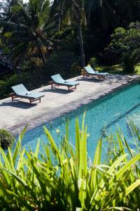 three lounge chairs sitting next to a swimming pool at Gaia-Oasis Mountain Abasan in Tejakula
