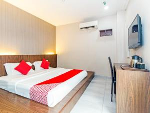 Schlafzimmer mit einem Bett mit roten Kissen und einem TV in der Unterkunft Super OYO 340 Comfort Hotel in Kampong Batu Belah