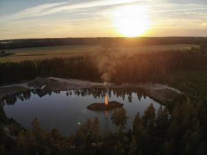 une île au milieu d'un lac au coucher du soleil dans l'établissement Metsjärve apartments, à Põlva