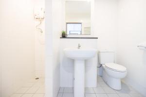 a white bathroom with a toilet and a sink at The Fifth Residence in Bangkok