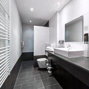 a bathroom with a sink, toilet, and bathtub at City Hotel Bergen op Zoom in Bergen op Zoom