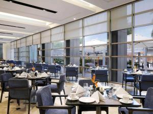 a restaurant with tables and chairs and large windows at Novotel Hyderabad Convention Centre in Hyderabad