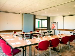 una sala conferenze con tavoli e sedie rosse di ibis Avranches Mont St Michel a Saint-Quentin-sur-le-Homme