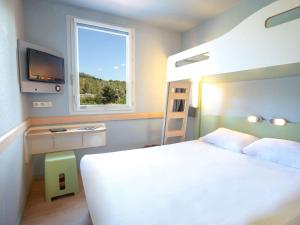 een slaapkamer met een wit bed en een raam bij ibis budget Brignoles Provence in Brignoles