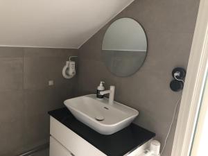 a white sink sitting under a mirror in a bathroom at Berglings Boutique Hotell in Norrtälje