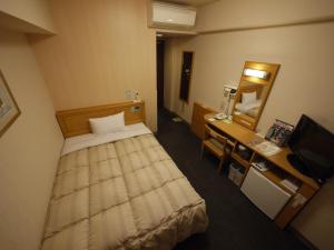 a bedroom with a bed and a desk and a mirror at Hotel Route-Inn Sakata in Sakata