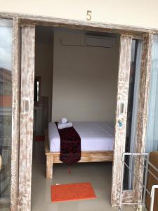 a small bed in a wooden frame in a room at Laksmi Guest House in Canggu