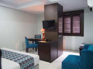 una camera d'albergo con un letto, una scrivania e una TV di Hotel Alma a Giacarta