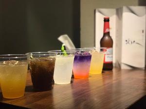 Just Live Inn-Taipei Station في تايبيه: مجموعة من أربعة مشروبات جالسين على طاولة خشبية