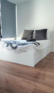 a white bed in a room with a wooden floor at ReadySet Apartments at City Tower in Melbourne