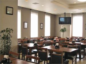 a restaurant with tables and chairs and a flat screen tv at Hotel Route-Inn Shinjyo Ekimae in Shinjo