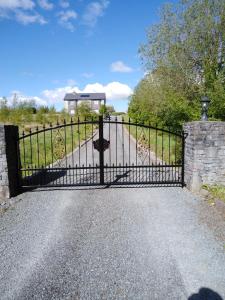 a black iron gate with a road behind it at Golden Rose House in Knock