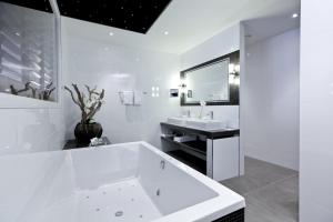 a white bathroom with a large tub and a sink at Hotel Thermen Bussloo - Apeldoorn in Bussloo