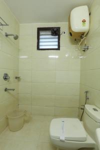 a white bathroom with a toilet and a window at Twin Tree in Kotagiri