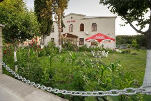 a chain fence in front of a house with a garden at Hotel Kakhaberi in Tʼetʼri Tsqaro