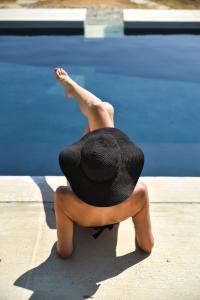 Una mujer con sombrero sentada junto a una piscina en Archipelagotinos, en Agios Romanos