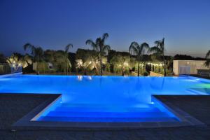 una gran piscina por la noche con luces azules en L'Ulivo e la Stella, en Porto Cesareo