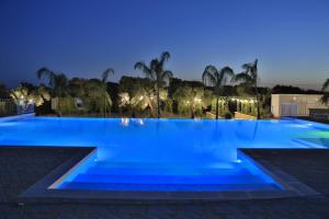 uma grande piscina à noite com luzes azuis em L'Ulivo e la Stella em Porto Cesareo