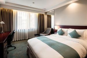 una habitación de hotel con una cama grande y una silla en Sunshine Hotel, en Seúl