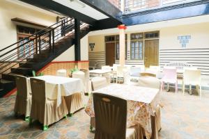 una stanza con tavoli, sedie bianche e scale di Andrin Daspatt Hotel a Makassar