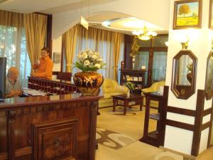 a woman standing in a lobby with a vase of flowers at Hotel Ami in Baile Felix