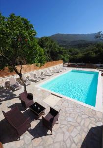a swimming pool with chairs and a table next to it at Dallas Valtos Studios in Parga