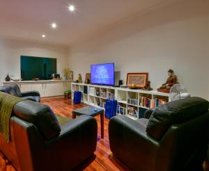 a living room with two leather chairs and a television at Crossroads Ecomotel in Port Augusta