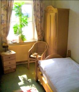 a bedroom with a bed and a chair and a window at Hotel Alt Wassenberg in Wassenberg