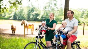 eine Familie auf Fahrrädern mit Pferden im Hintergrund in der Unterkunft TopParken – Résidence de Leuvert in Cromvoirt