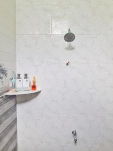 a white tiled bathroom with a shower and a sink at Mawar Dayana Homestay in Jertih +25 photos