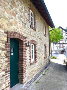 un edificio de ladrillo con una puerta verde. en Freistaat Eifel en Nettersheim