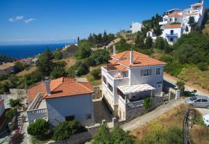 een wit huis met een rood dak op een heuvel bij Likavgies Comfort Maisonettes in Alonissos stad