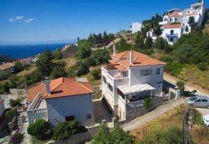 une maison blanche avec un toit rouge sur une colline dans l'établissement Likavgies Comfort Maisonettes, à vieille ville d'Alonissos