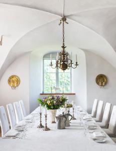 a dining room with a long table with chairs and a chandelier at Västanå Slott in Gränna