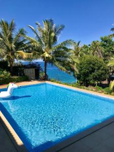 een zwembad met palmbomen en de oceaan bij Anoi Itam Resort in Sabang