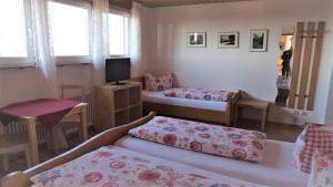 a room with two beds and a table and a television at Pension Seliger in Meersburg