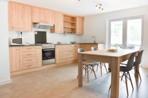 una cocina con armarios de madera y una mesa con sillas. en Tamarin Chambres d'Hotes, en Tamarin