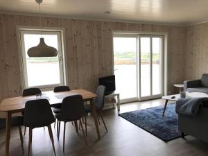 a dining room with a table and chairs and a television at Nappstraumen seafront cabin in Leknes
