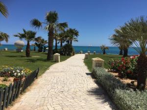 un chemin menant à la plage avec des palmiers et des fleurs dans l'établissement La mer carrément à vos pieds, à Hammamet