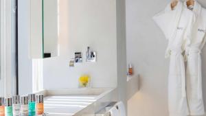 ein weißes Badezimmer mit einem Waschbecken und einem Spiegel in der Unterkunft ABaC Restaurant Hotel Barcelona GL Monumento in Barcelona