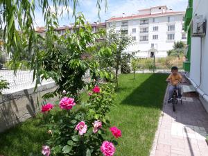 a young boy riding a bike in a yard with pink roses at Dr Aslan Apart Hotel in Esenboga