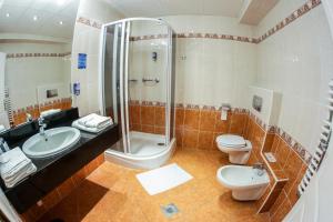 a bathroom with a shower and a toilet and a sink at Hotel Silver in Hajdúszoboszló