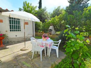 stół z krzesłami i parasol w ogrodzie w obiekcie Apartment Il Gelsomino by Interhome w mieście La Collina