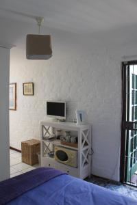 a bedroom with a bed and a tv on a shelf at Delightful Surrey Street in Cape Town